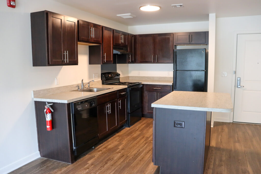 Interior of Centerton Village - an empty kitchen with dark cabinets and an island. 