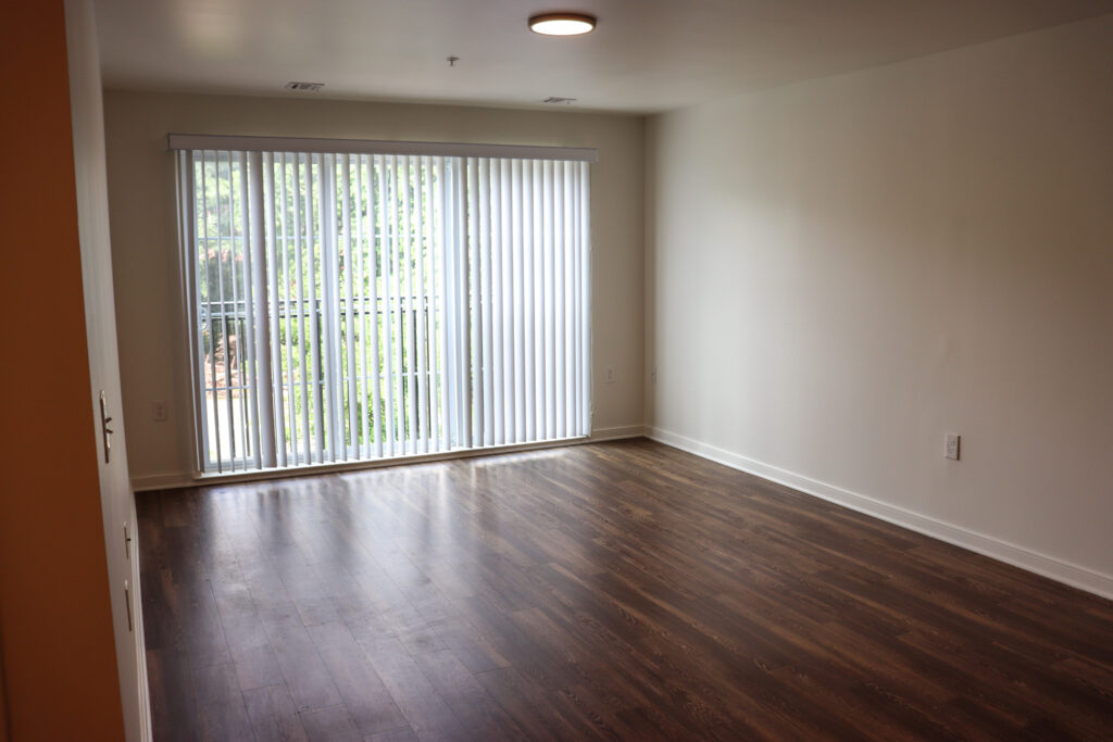 Interior of Centerton Village - an empty living room with a large sliding glass door to the outside.