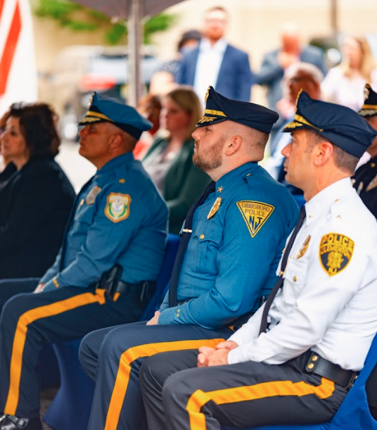 Law enforcement officers sit in the audience at a press event.