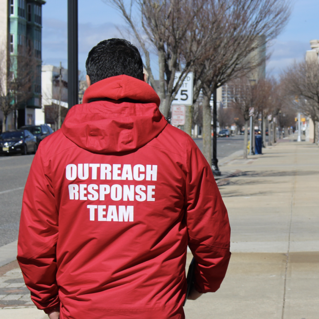 A staff members walks away from the camera wearing a jacket with the words "Outreach Response Team"