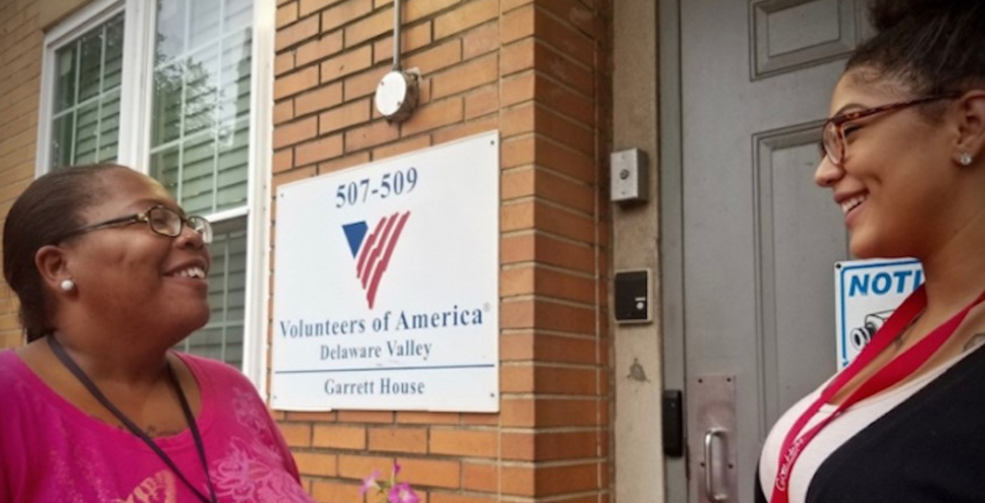 A Garrett House staff member and client speak on the step of the building.