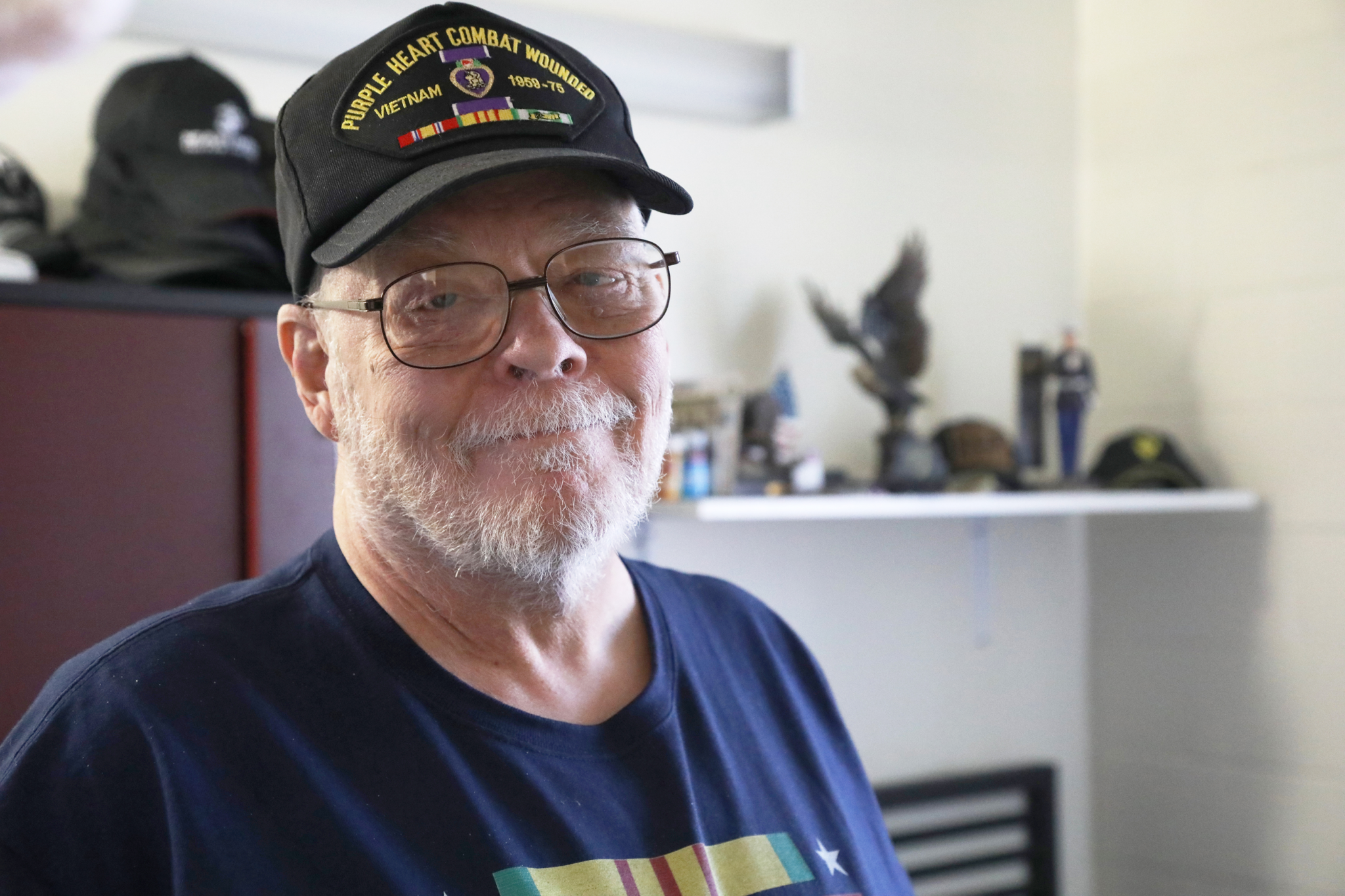 An older veteran looks at the camera with a small smile.